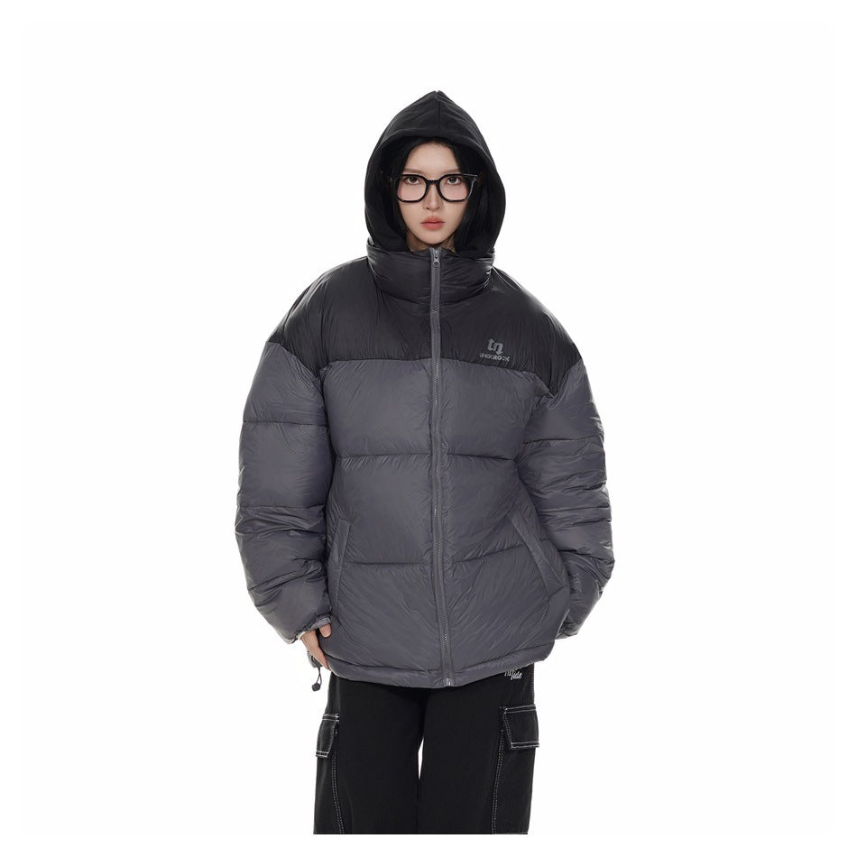 Front view of a model wearing a charcoal-gray and black color-block puffer jacket with the hood up.