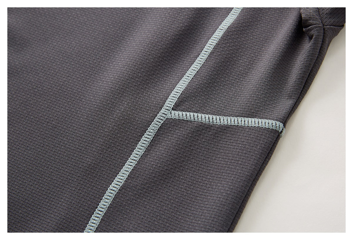 Close-up of charcoal fabric with pale blue contrast stitching along a seam.