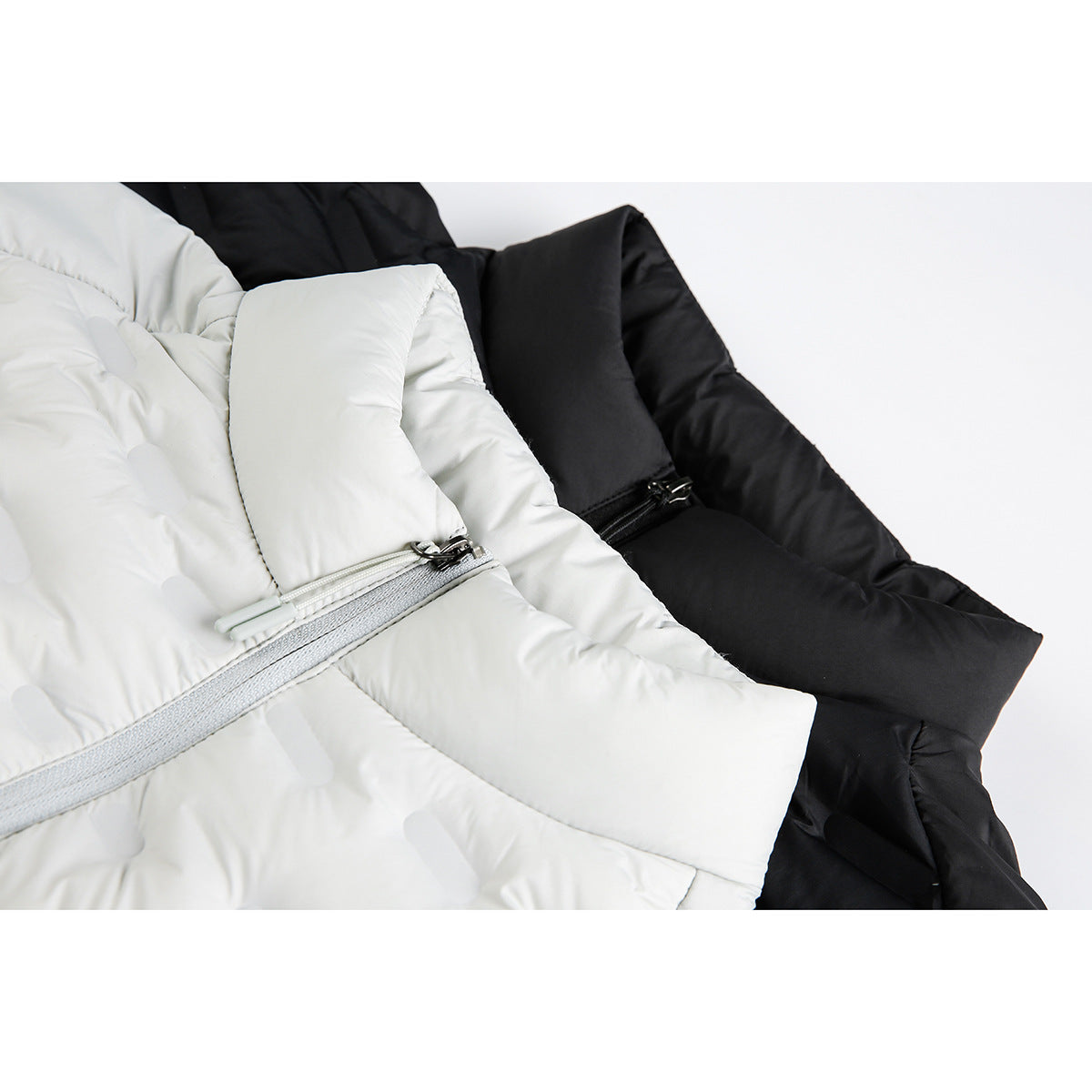 Close-up of white and black quilted jackets, showing the front zippers and padded panels.