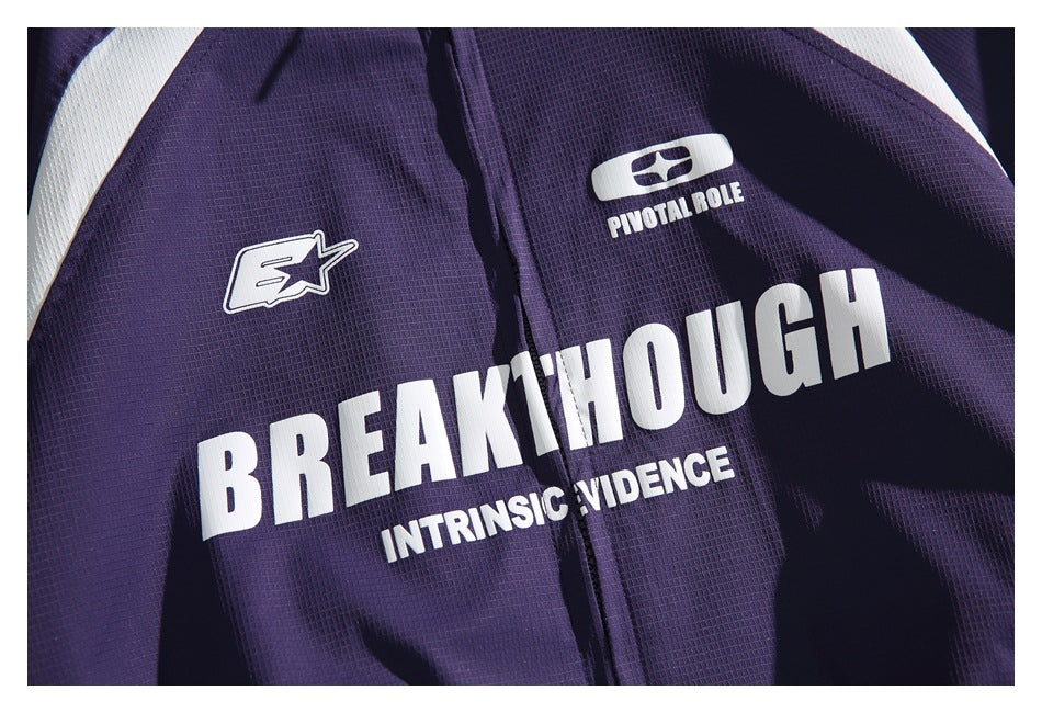 Close-up of white graphic lettering and emblems printed on the purple jacket's front.