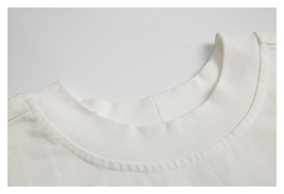 Close-up of the ribbed crew neckline and shoulder seam of an off-white T-shirt.