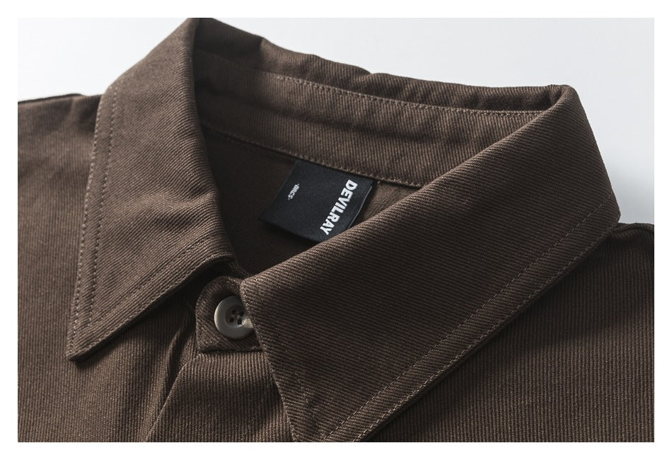 Close-up of the dark brown shirt's pointed collar, button, stitching, and inner neck label.