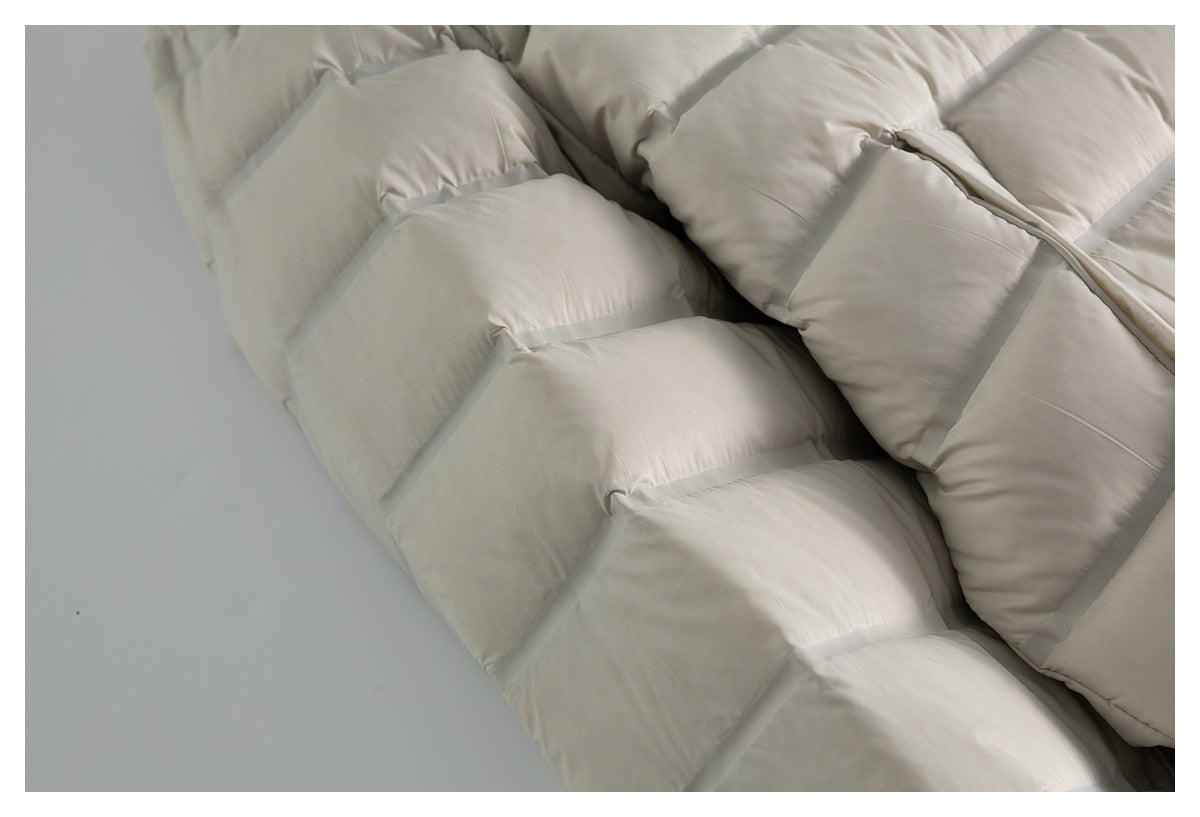 Close-up of the padded horizontal quilting on a cream puffer jacket.