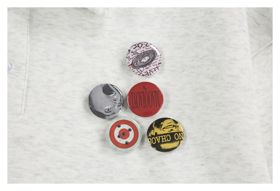 Five round graphic badges arranged on the front of a light gray marled garment.
