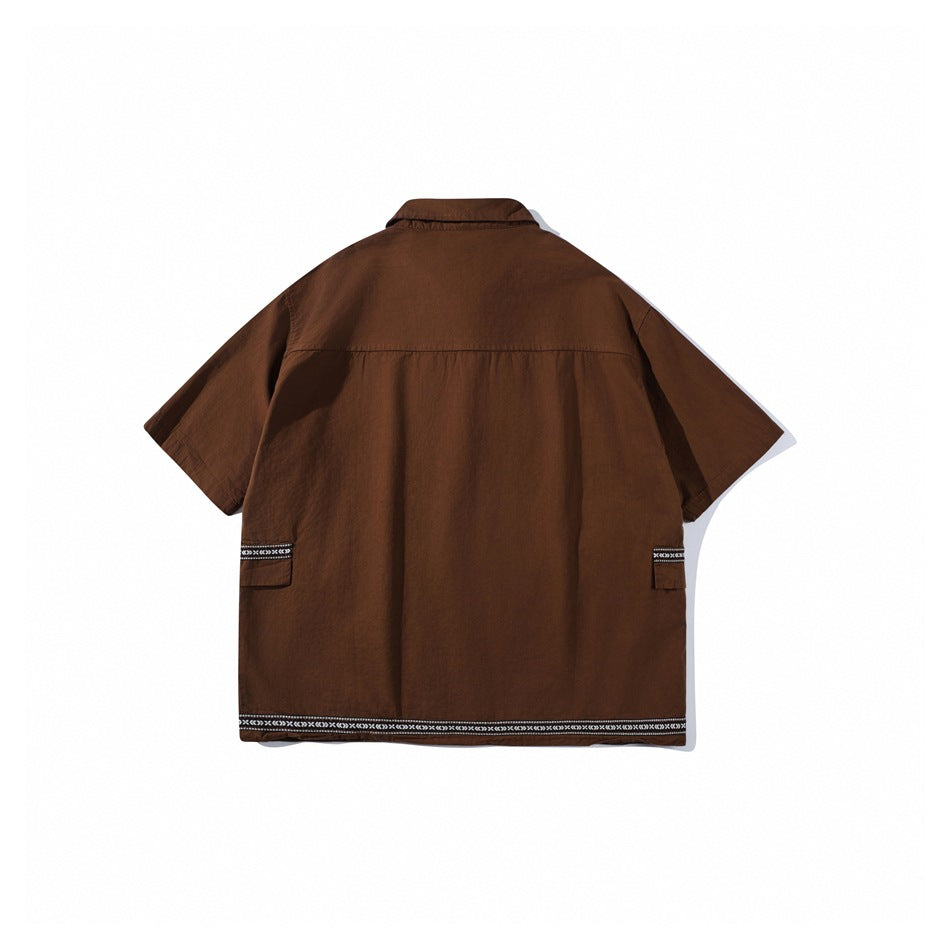 Back view of a brown short-sleeve collared shirt with patterned trim along the hem and pocket flaps.