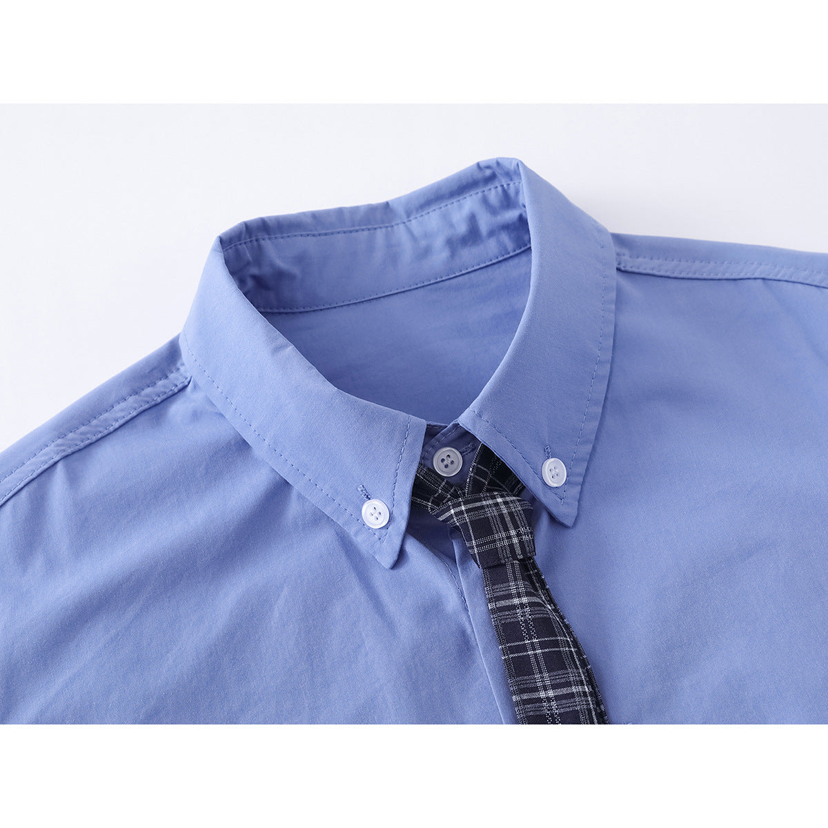 Close-up of a light blue button-down shirt collar with white buttons and a black plaid tie.