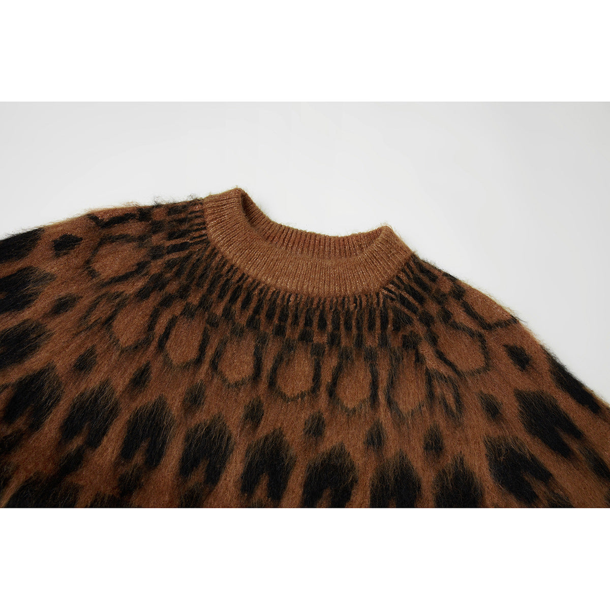Close-up of a brown knit sweater's ribbed crew neck and dark patterned yoke.