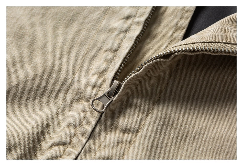 Close-up of a metal zipper and pull on taupe-beige fabric.