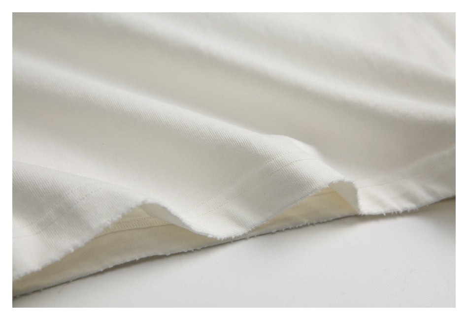 Close-up of ivory-white fabric with a raw, slightly frayed cut edge and visible weave.