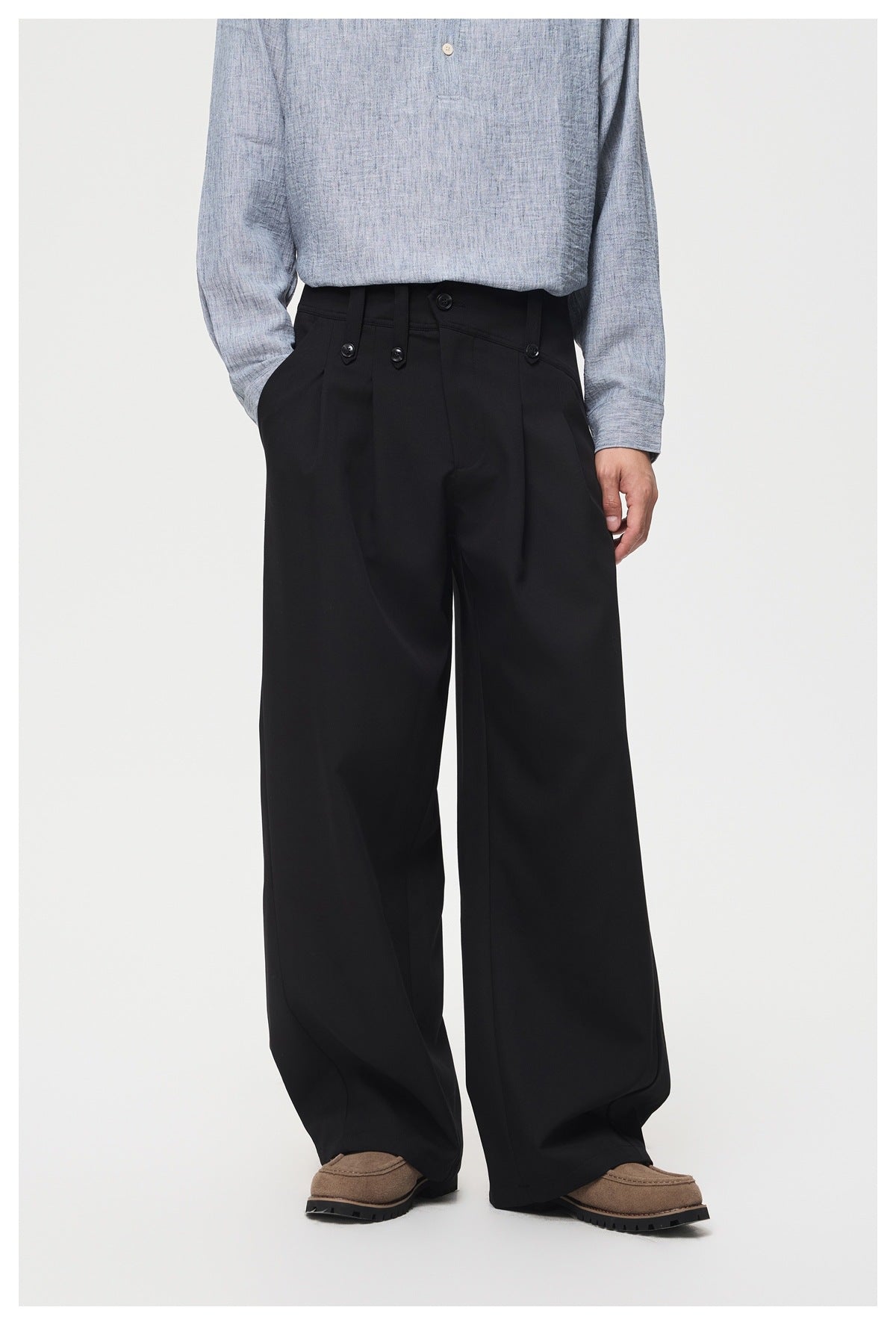 Front view of black wide-leg trousers on a model, showing the high buttoned waistband and front pleats.