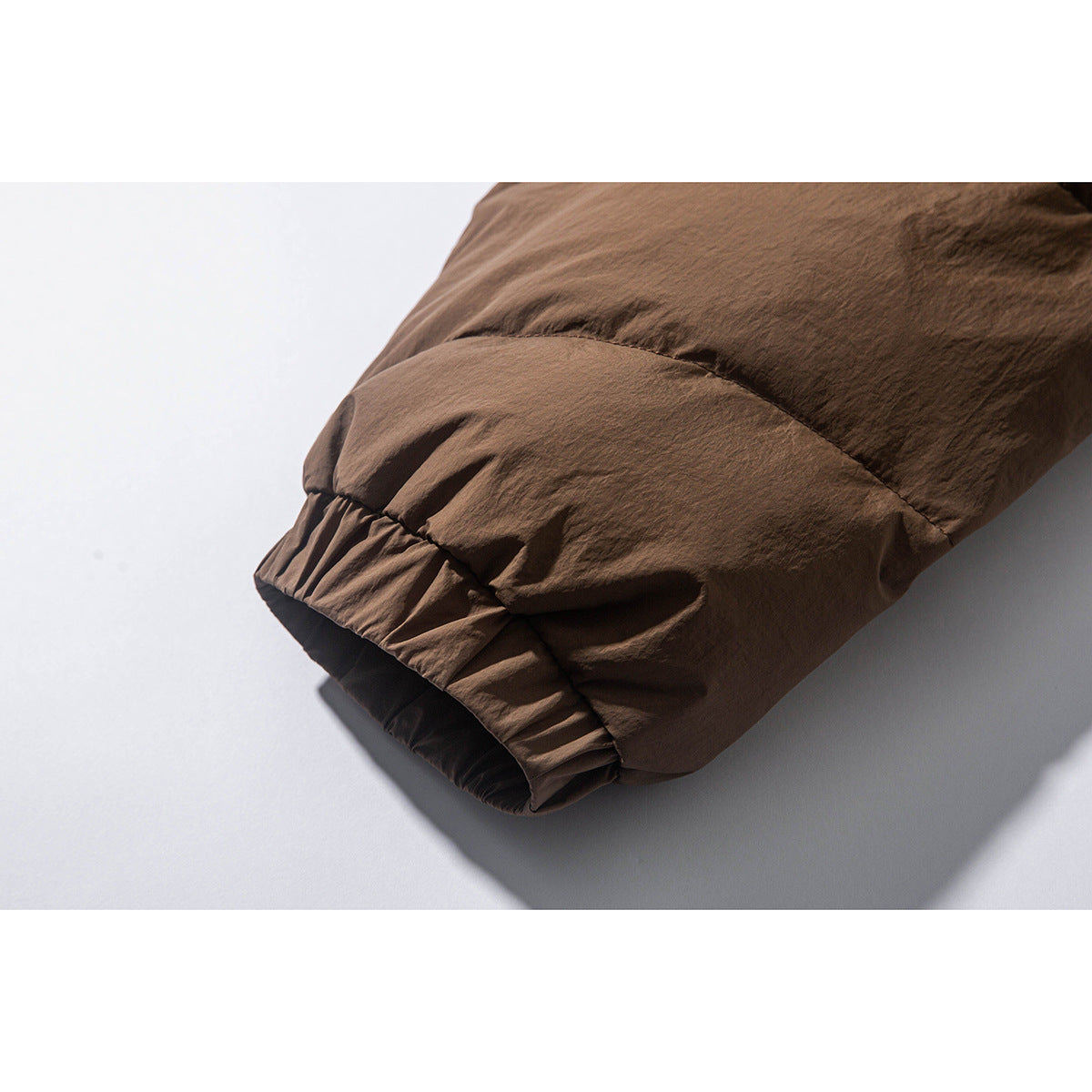 Close-up of the brown jacket's gathered sleeve cuff and padded seam.