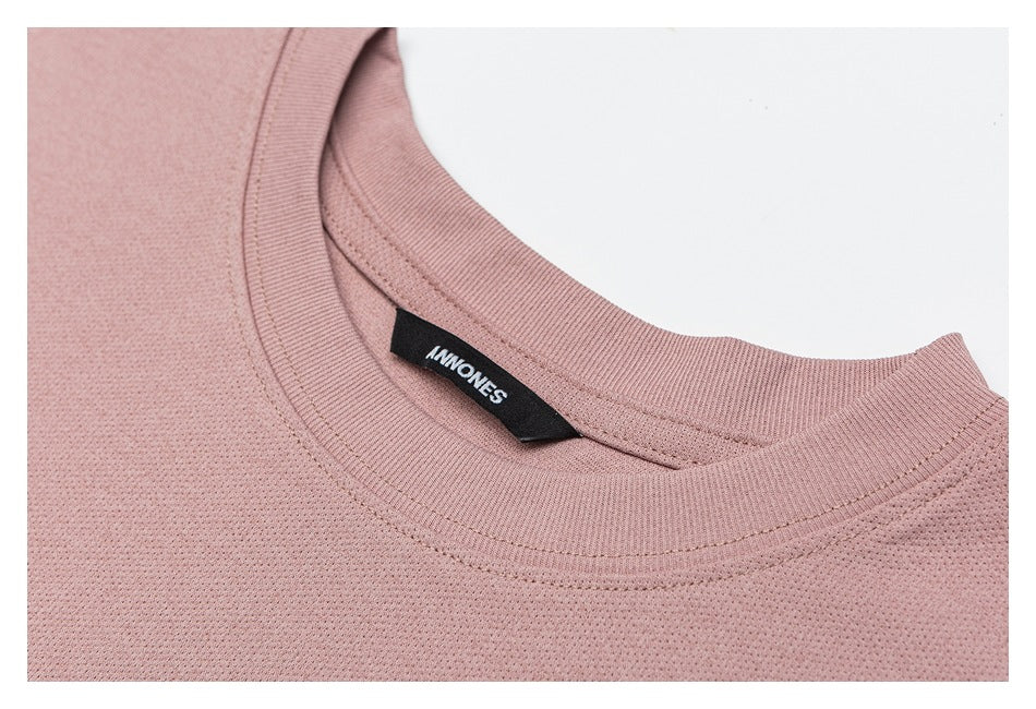 Close-up of a dusty rose shirt’s ribbed crew neck and black woven “ANNONES” label.