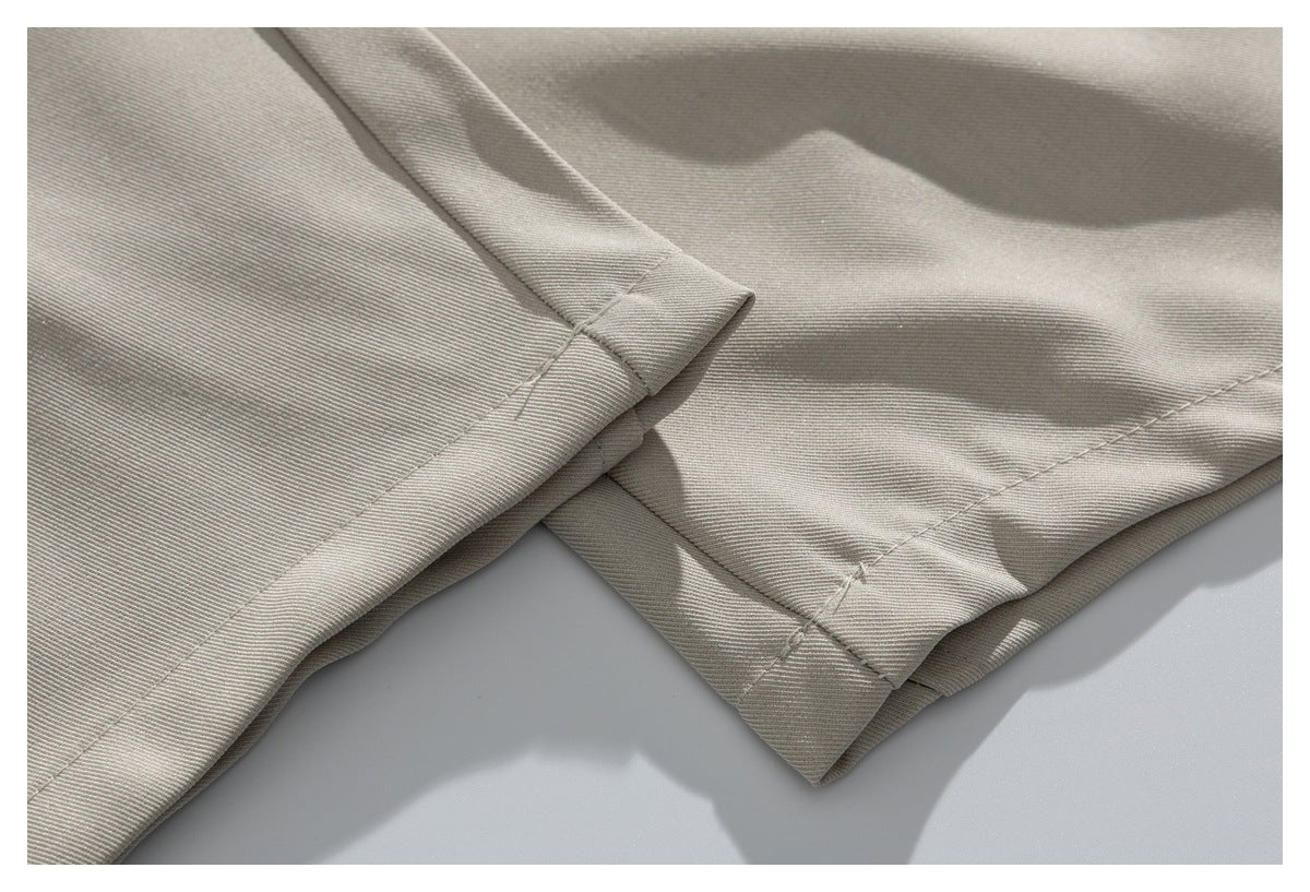 Close-up of beige trouser leg hems with visible stitching and folded edges.