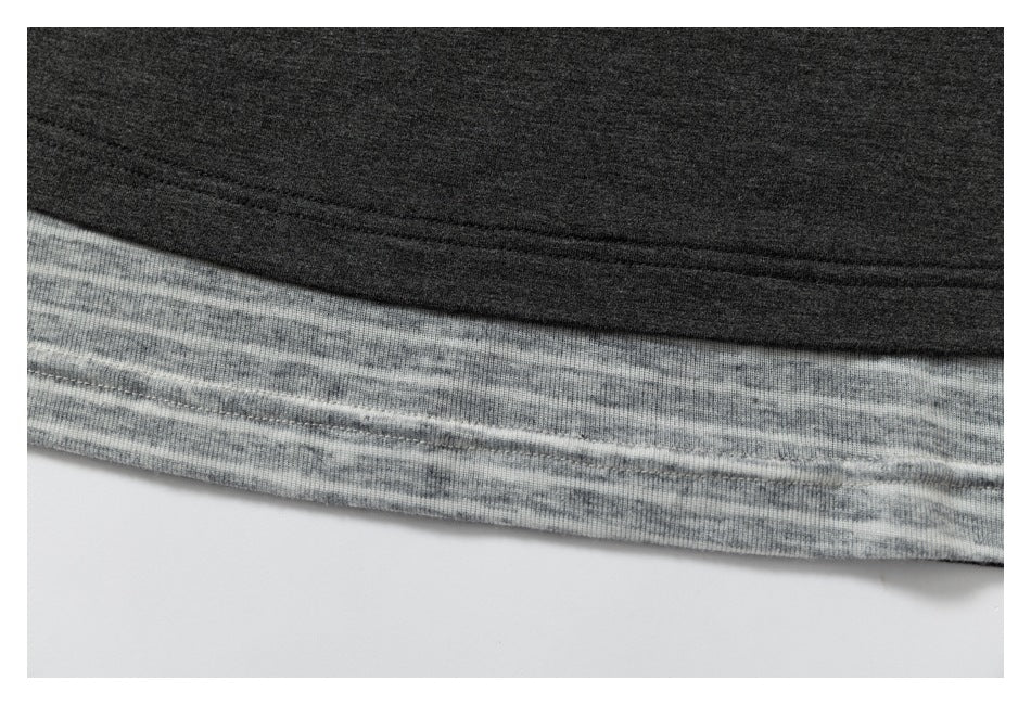 Close-up of a dark charcoal garment hem layered over a light gray heathered band with visible stitching.
