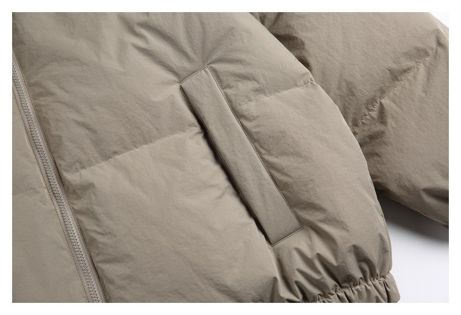 Close-up of a vertical pocket on the taupe padded jacket, with part of the sleeve and gathered hem visible.
