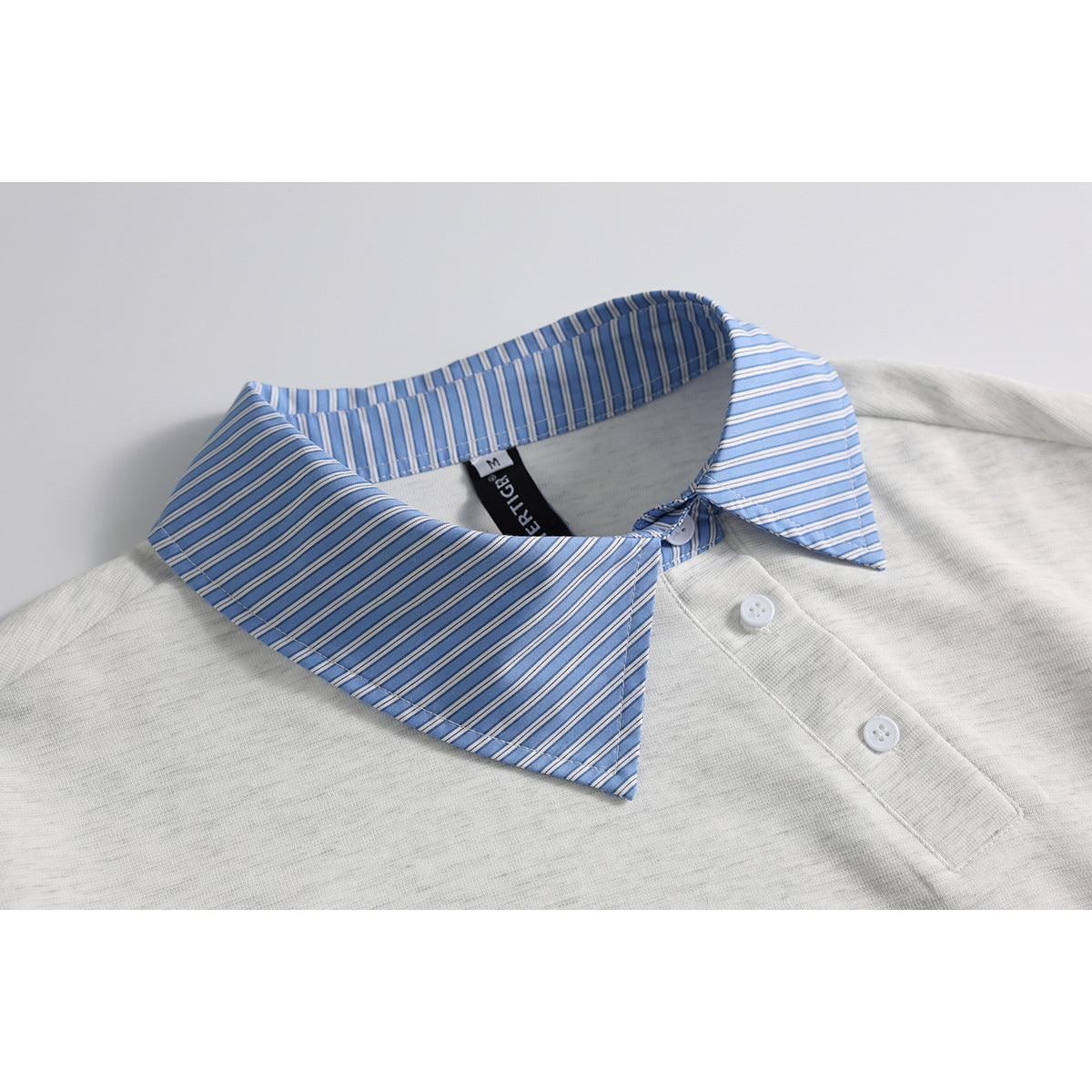 Close-up of an off-white polo shirt with a blue striped collar and white buttons.