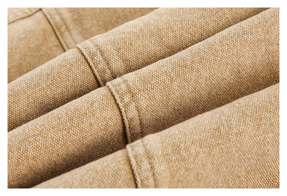 Macro view of tan garment fabric folded into ridges, showing its textured weave and seams.