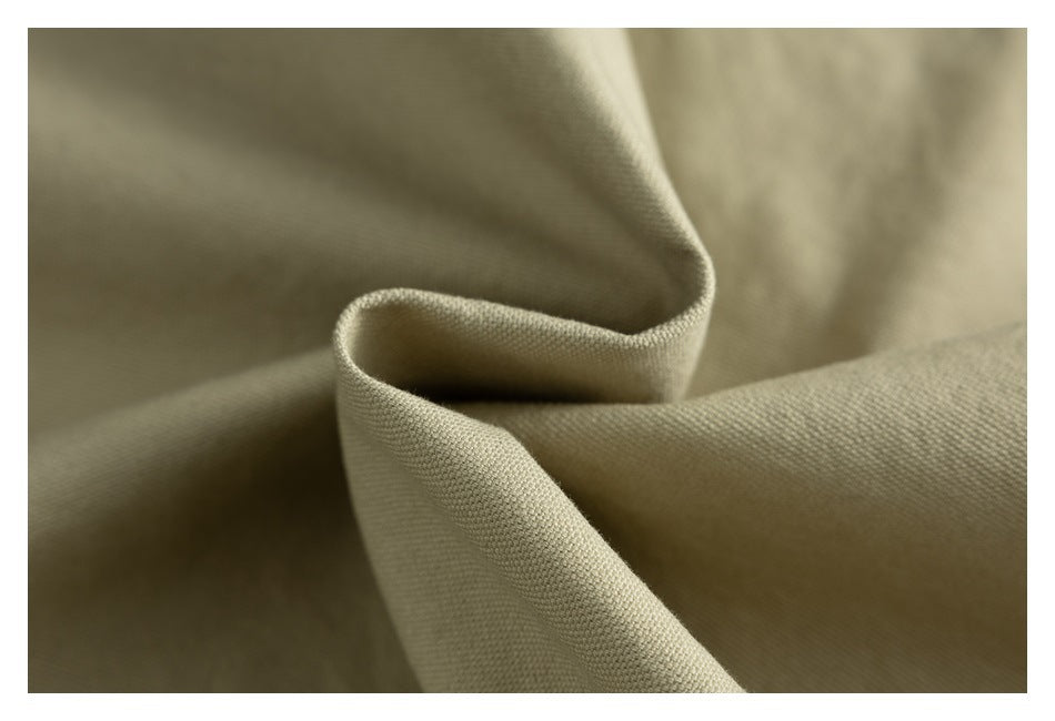 Macro view of khaki garment fabric folded to show its woven surface and drape.