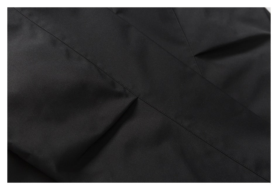 Close-up of black jacket fabric showing intersecting stitched seams and panels.