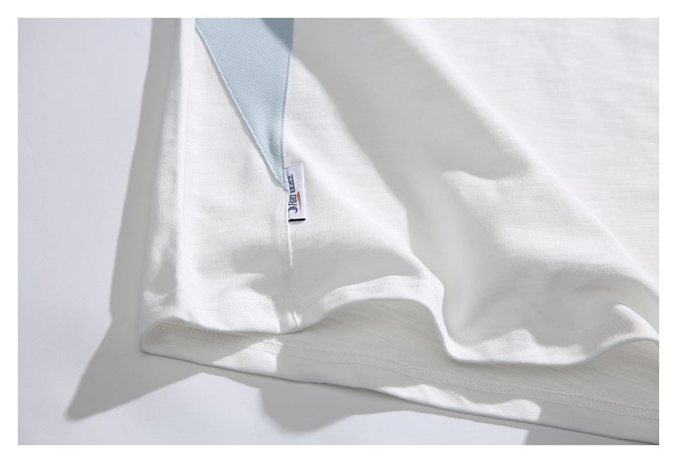 Close-up of the white T-shirt's bottom hem and small pale blue side insert.
