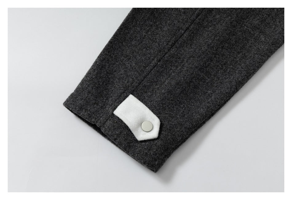 Close-up of a dark gray sleeve cuff with a white snap tab and round silver snap.