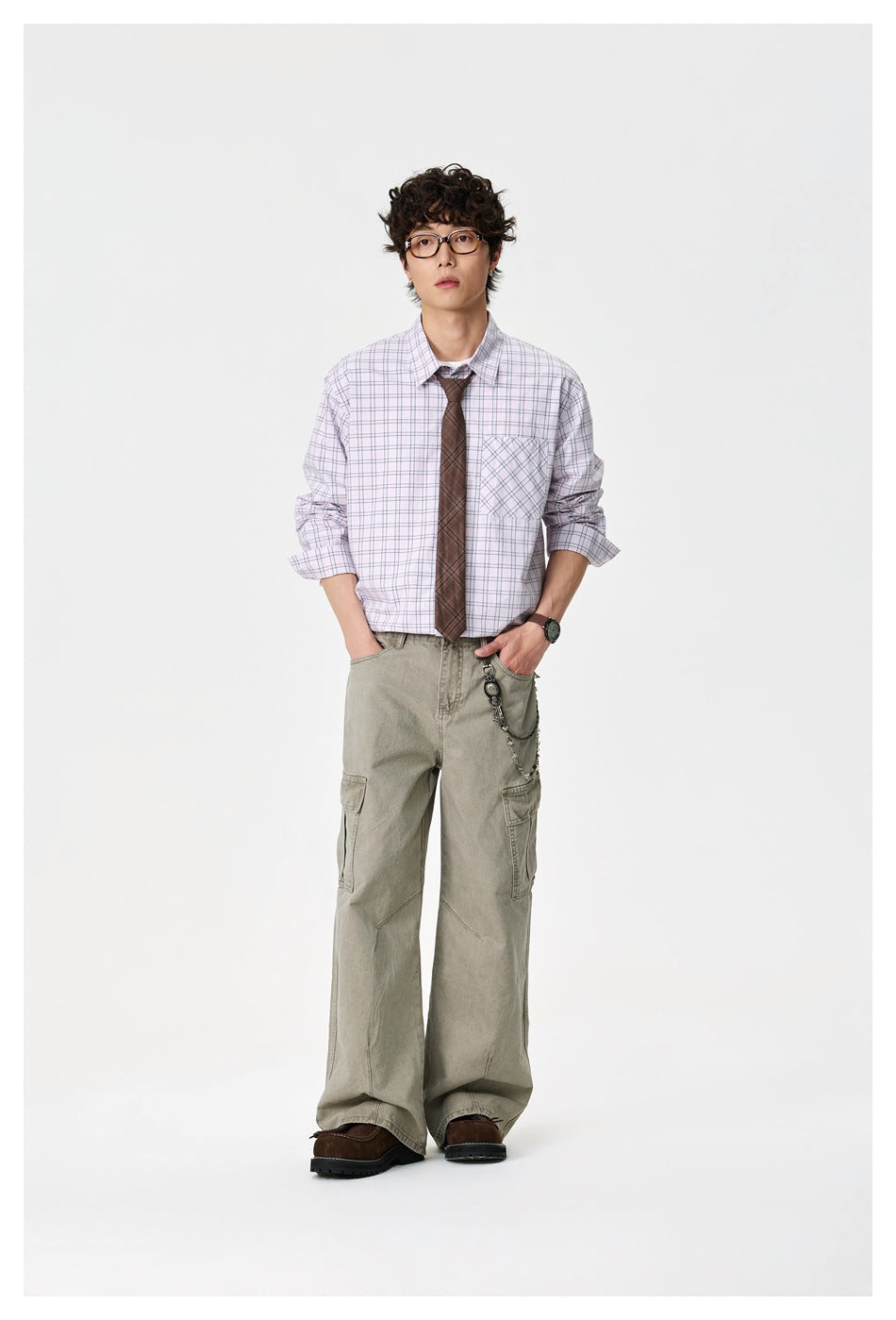 Full-length front view of a model in a pale lavender plaid button-down shirt, brown tie, and loose cargo pants.