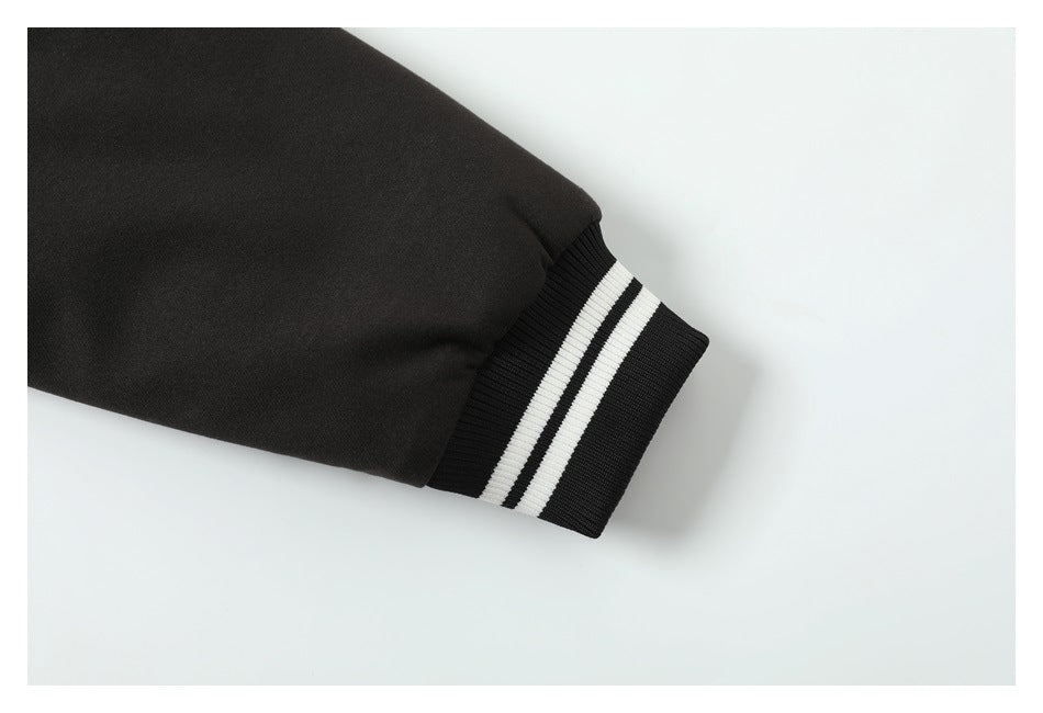 Close-up of a black jacket sleeve ending in a ribbed cuff with two white stripes.