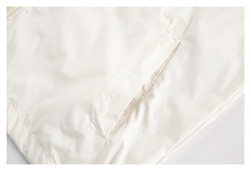 Close-up of an angled pocket opening and stitching on an off-white garment.