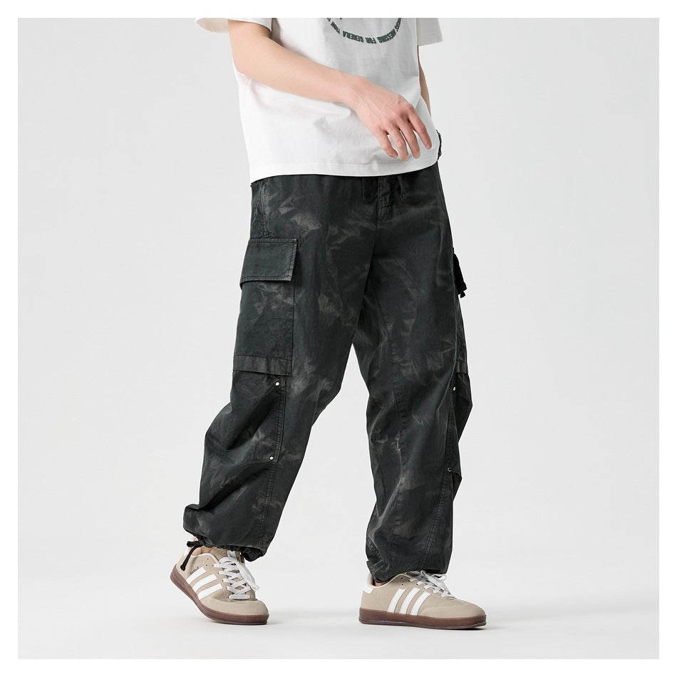 Angled view of a model wearing loose charcoal cargo pants with large flap pockets and gathered ankle cuffs.