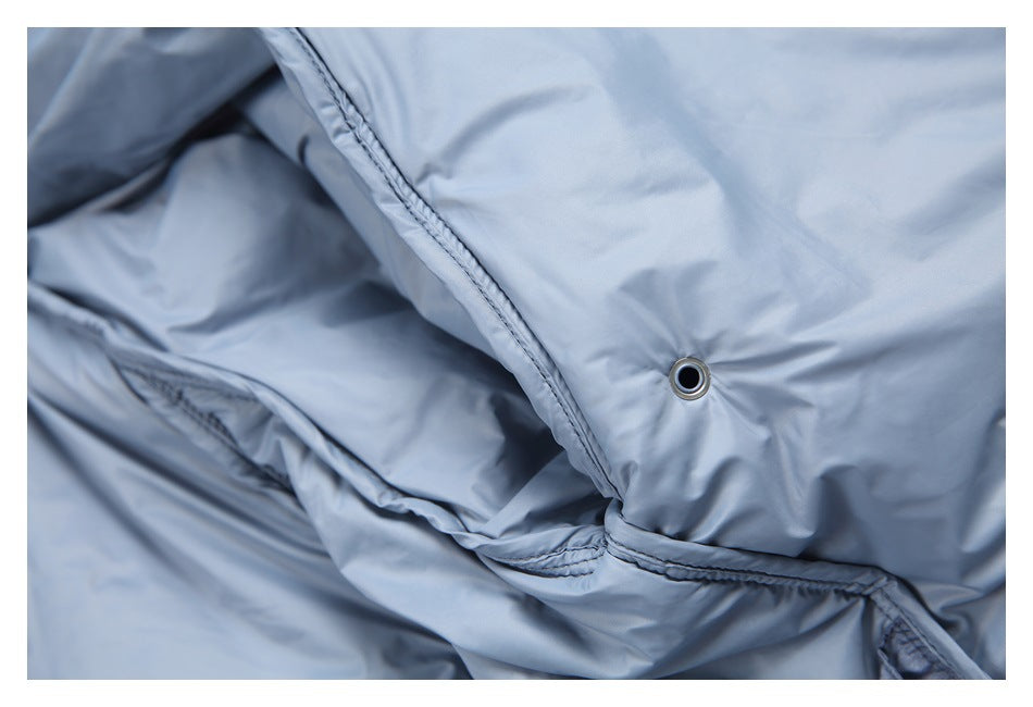 Close-up of light blue padded fabric with stitched seams and a small metal eyelet.