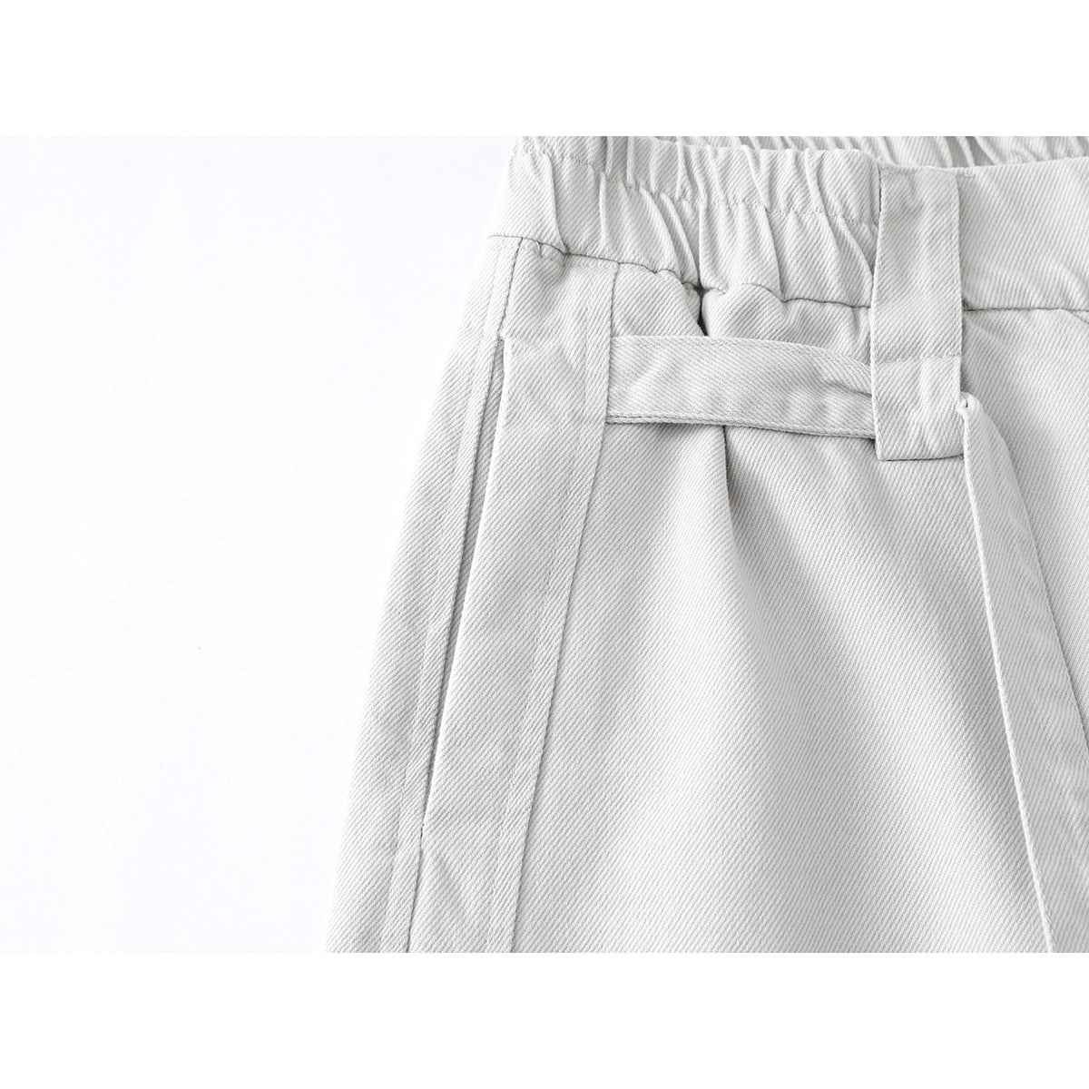 Close-up of light gray trousers showing the elastic waistband, belt loop, and side seam.