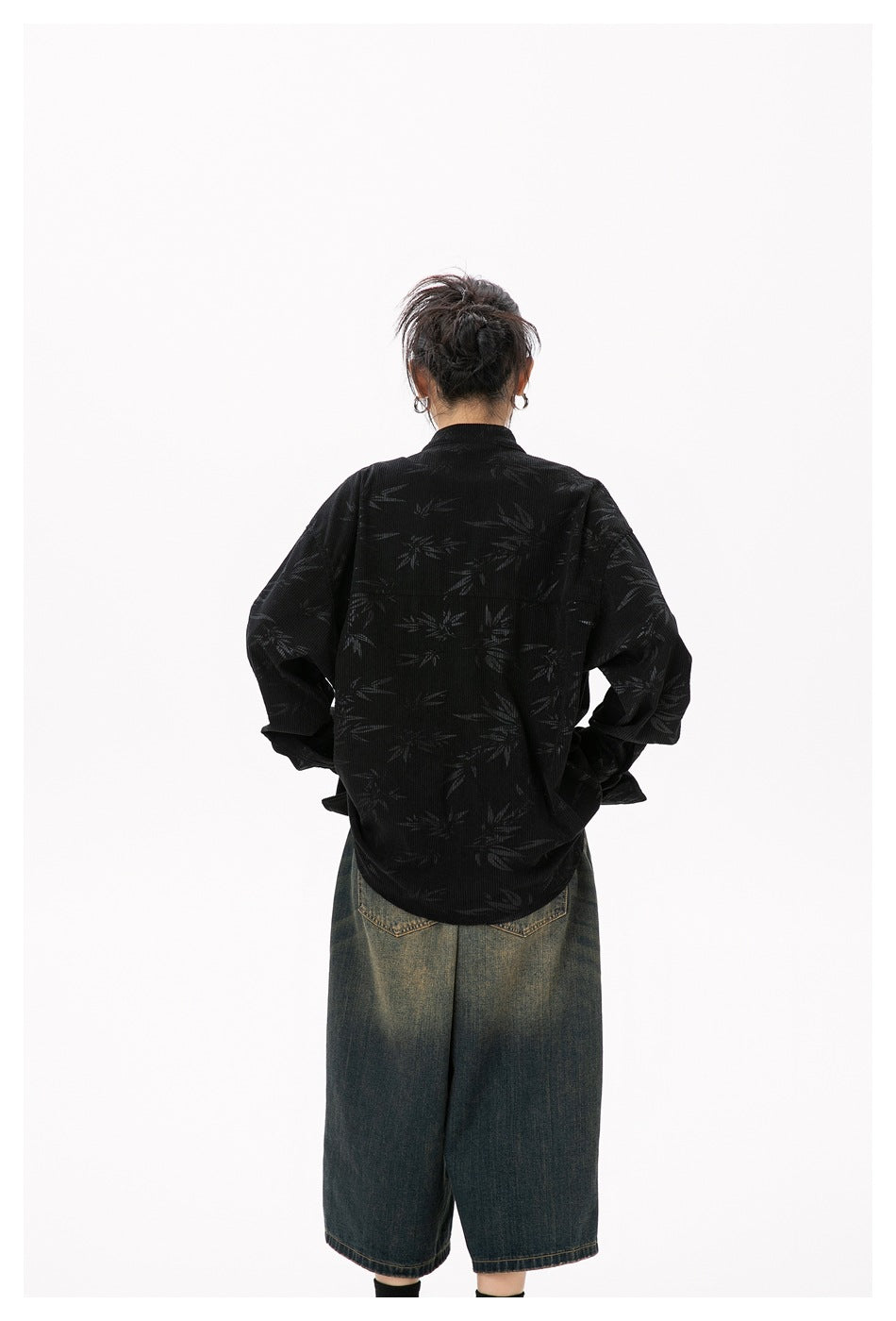 Rear view of a model wearing a black bamboo-patterned jacket and dark denim shorts.