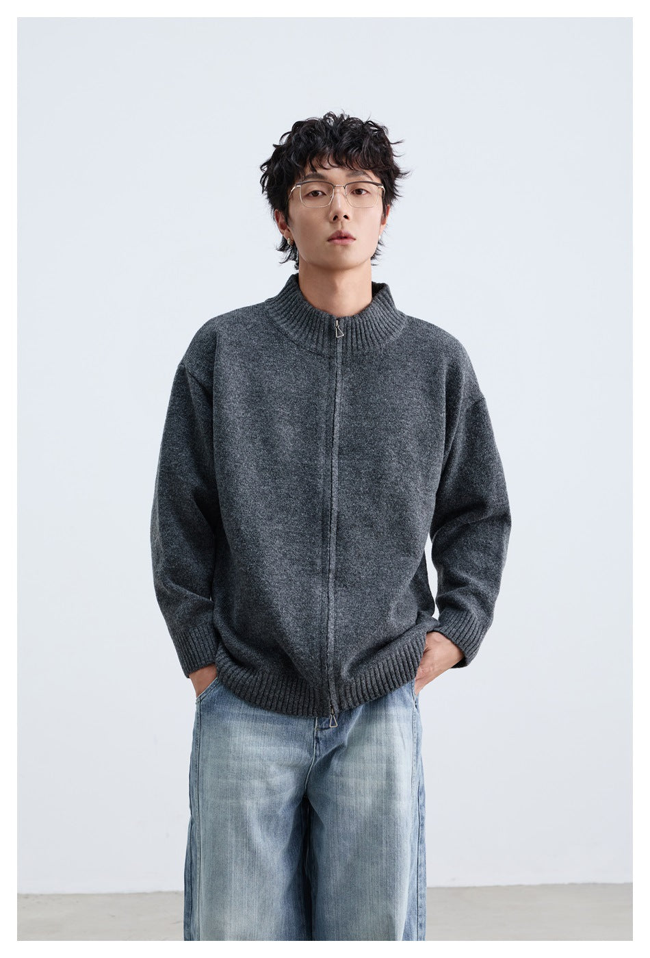 Front view of a man wearing a charcoal gray zip-front knit sweater with a ribbed collar, cuffs, and hem.