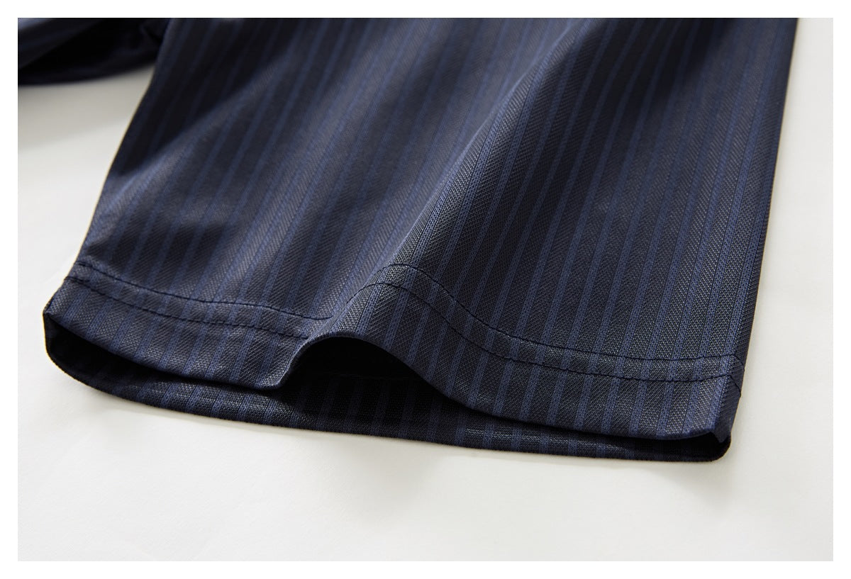 Close-up of the hem of a dark navy pinstriped shirt, showing the stitched edge and a side slit.