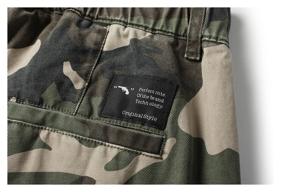 Close-up of a sewn black English-text label on camouflage pants above a stitched pocket.