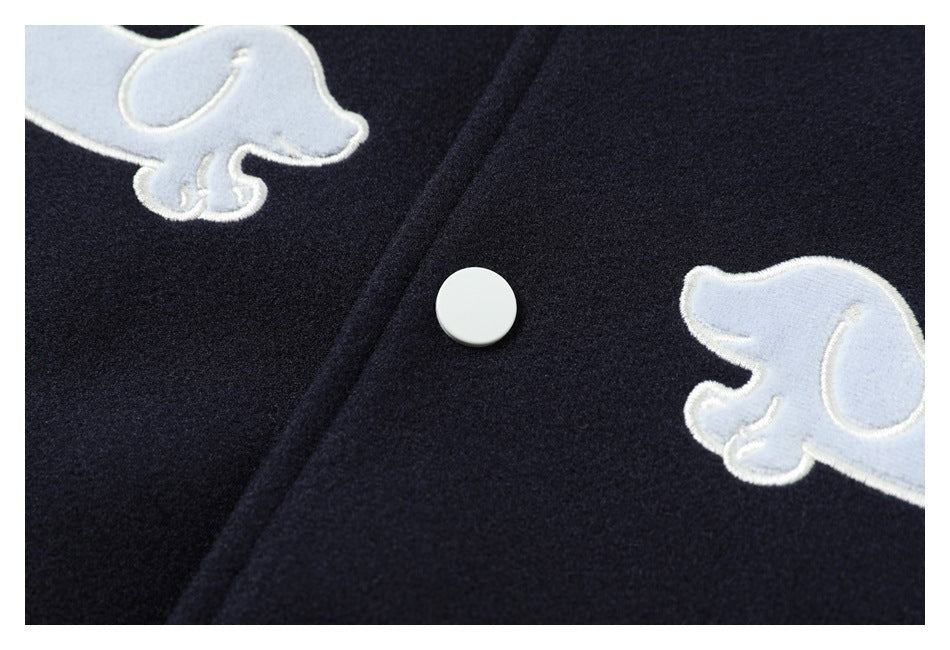 Close-up of two pale blue dog appliqués and a white snap button on navy jacket fabric.