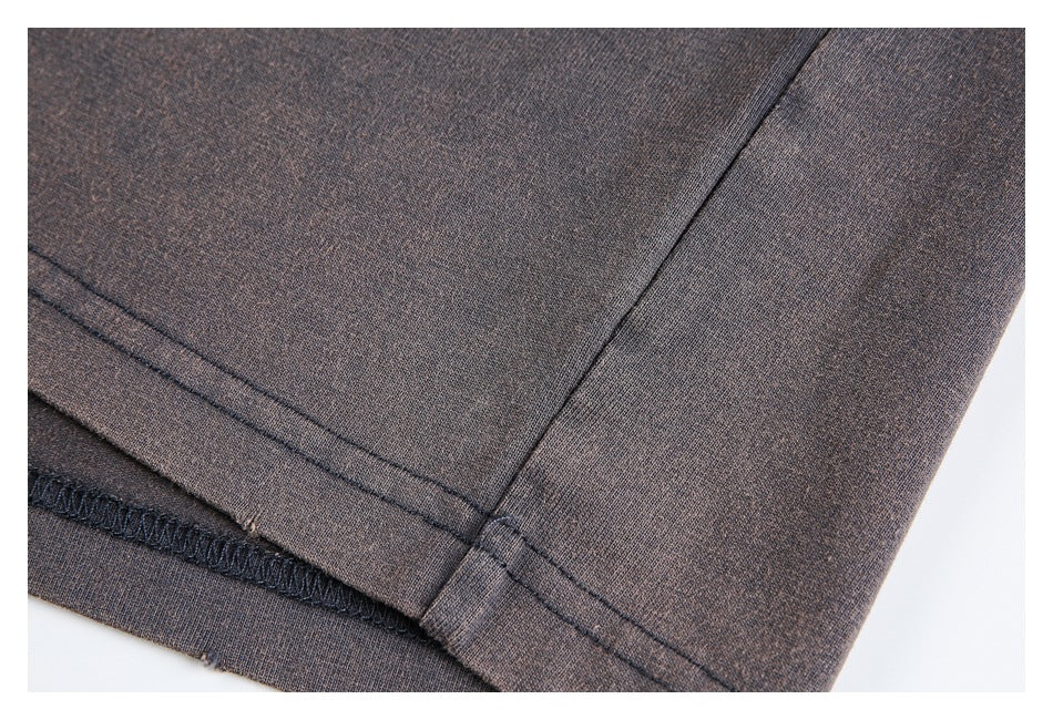 Close-up of a charcoal-brown garment hem with double stitching and an overlocked edge.