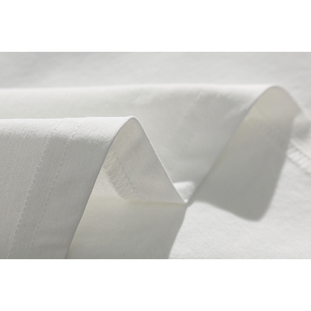 Close-up of the folded hem and stitching on a plain white T-shirt.