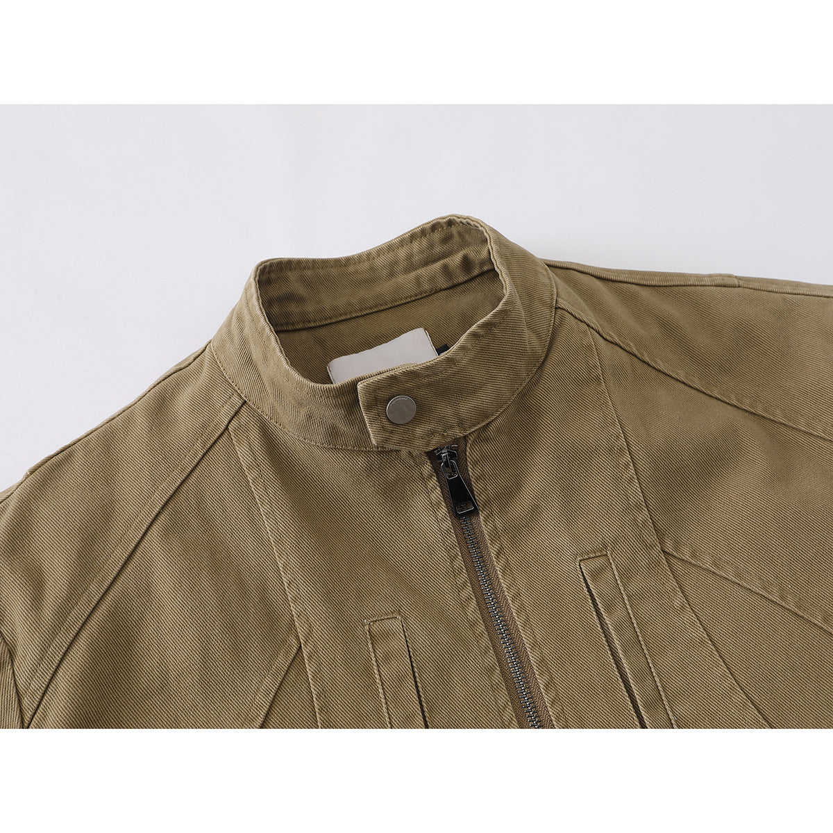 Close-up of a tan jacket's stand collar, snap button, front zipper, and stitched panels.