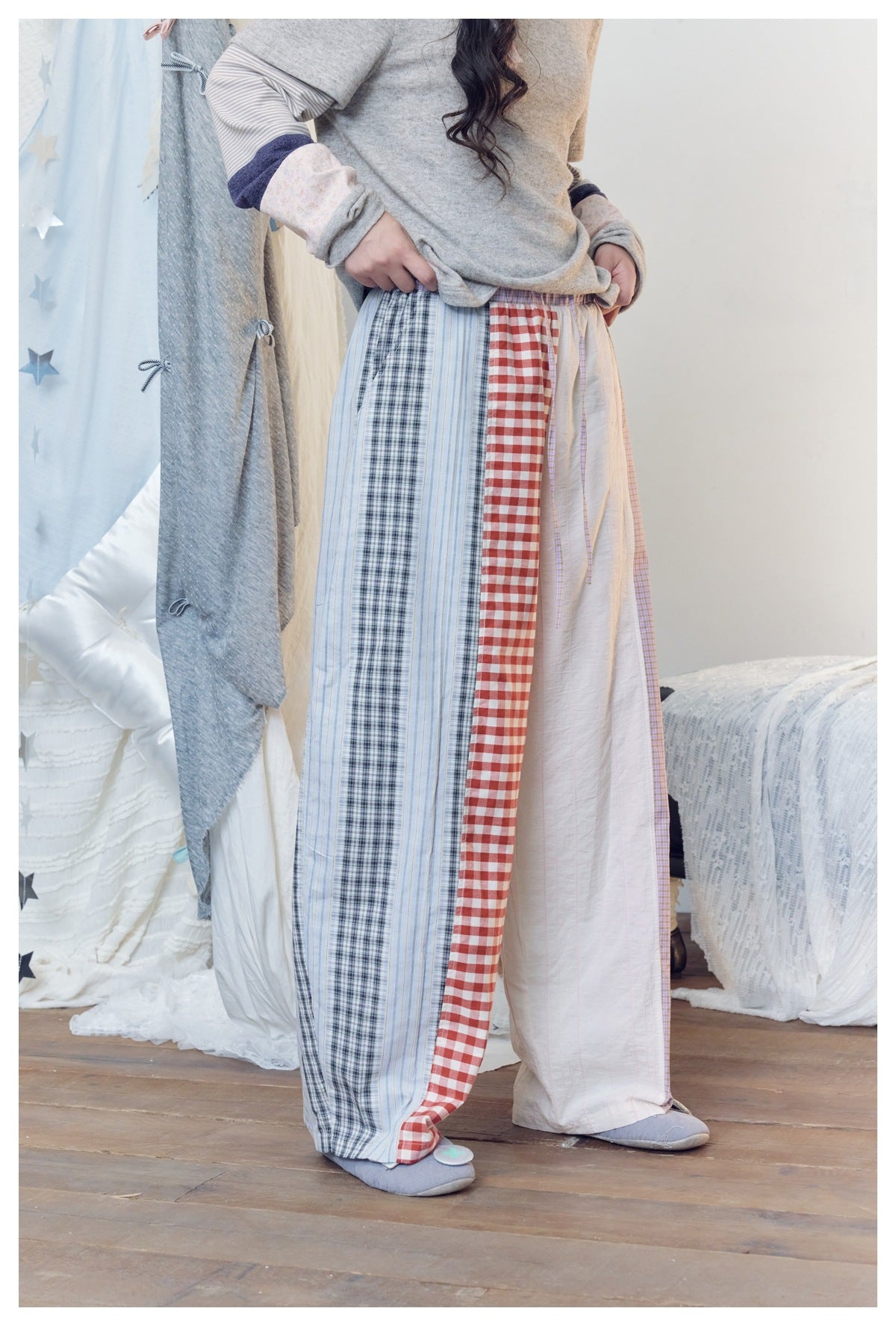 Model wearing wide-leg patchwork pants with red gingham, blue plaid and striped, white and lavender-check panels.
