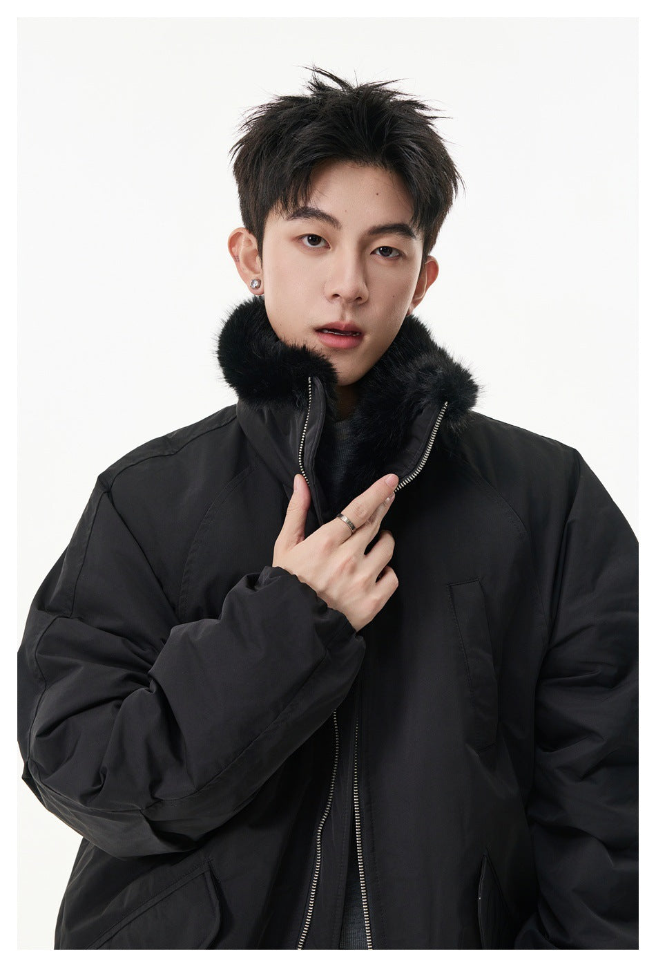 Close view of a model wearing a black jacket with a plush black collar and a front zipper.
