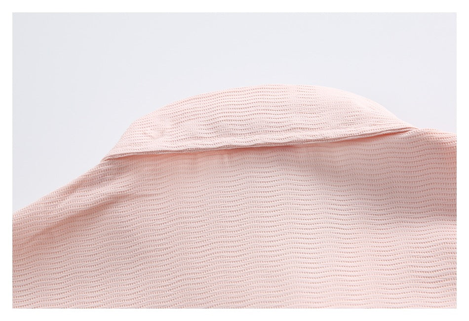 Close-up of the pale pink ribbed garment's folded collar and stitched seam.