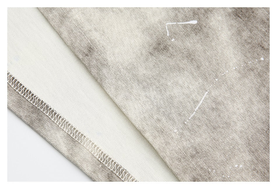 Close-up of gray-beige mottled fabric with an overlocked seam and scattered white marks.