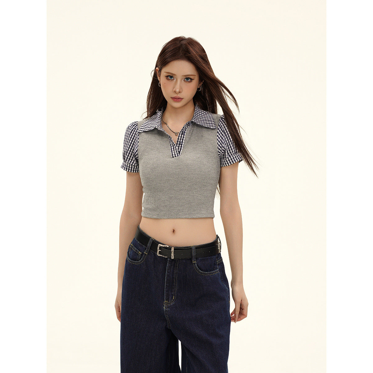 Front view of a model wearing a gray cropped top with a gingham collar, short puff sleeves, and dark jeans.
