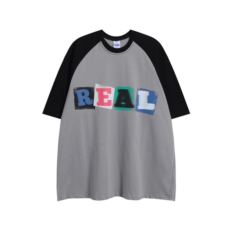 Gray raglan T-shirt with black sleeves and collar and a multicolor block-letter REAL print on the chest