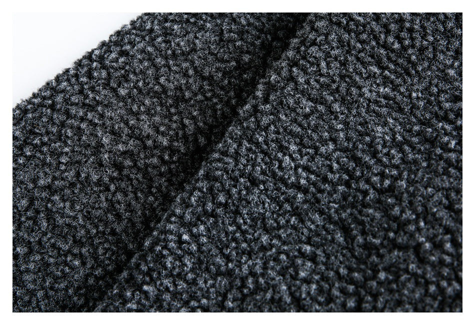 Extreme close-up of dark charcoal bouclé fabric, showing its raised looped texture and seam.