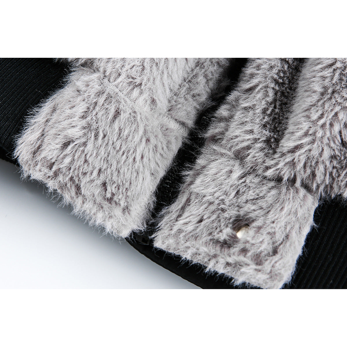 Close-up of gray fuzzy jacket fabric beside a black zipper and a small metal snap.