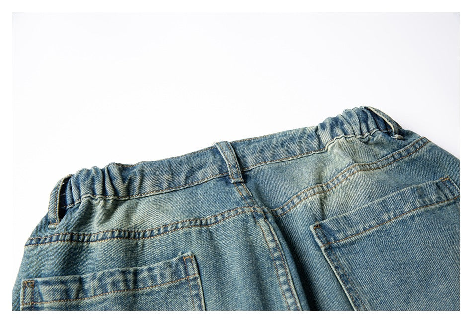Close-up of the back waistband of faded blue denim shorts, with elastic sections, belt loops, and rear pockets.