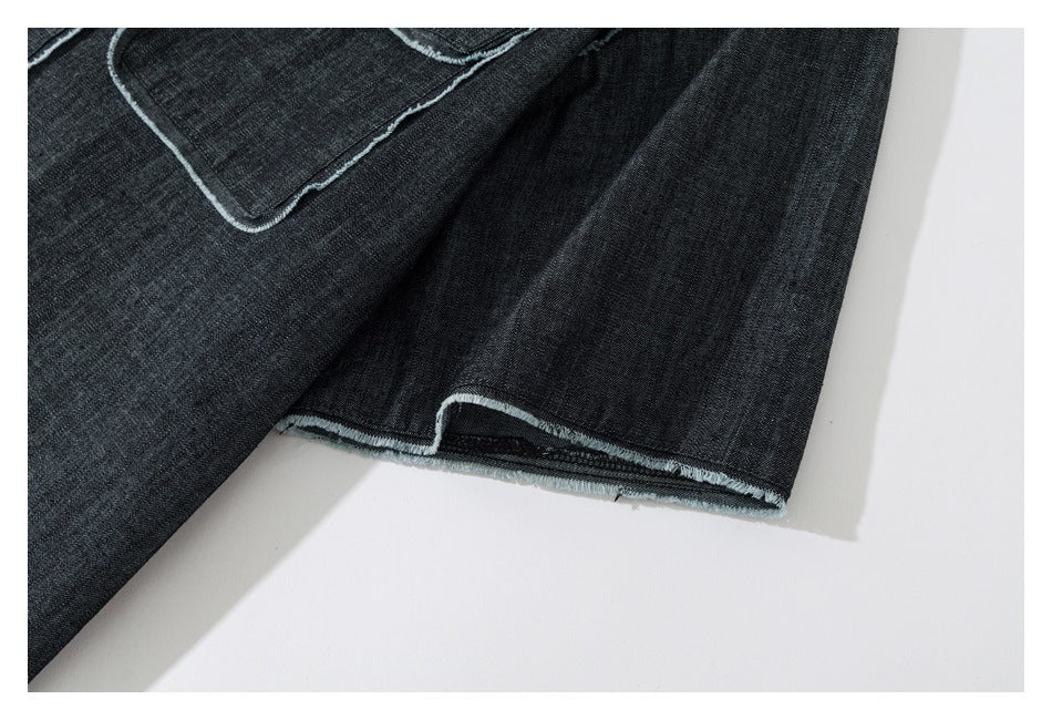 Close-up of a dark denim sleeve hem with frayed pale edging beside part of a pocket.