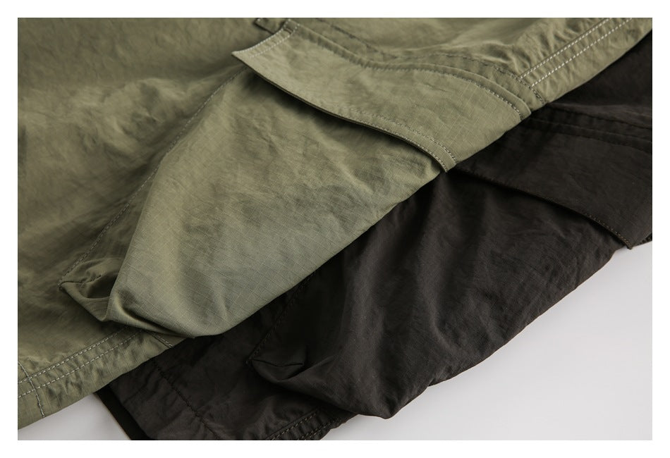 Close-up of olive and charcoal shorts layered to show stitching, pocket flaps and hems.